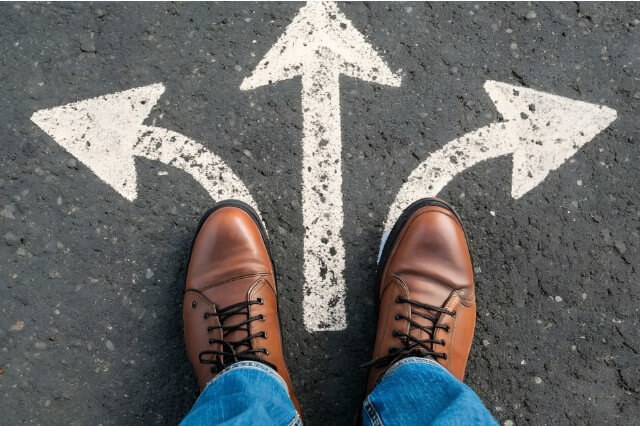 A person standing in front of three directional arrows