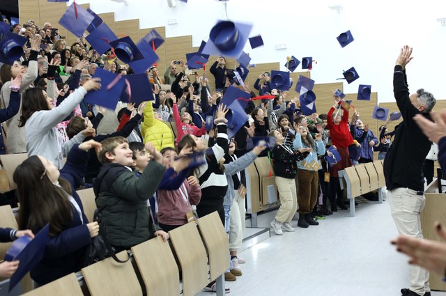 Bambine e bambini che lanciano il tocco in unaula universitaria
