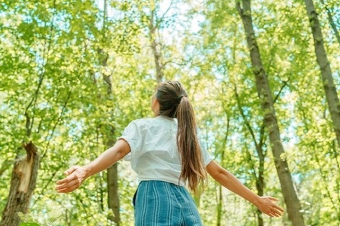 ragazza a braccia aperte in un bosco