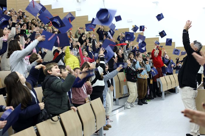 Bambine e bambini che lanciano il tocco in un'aula univesitaria