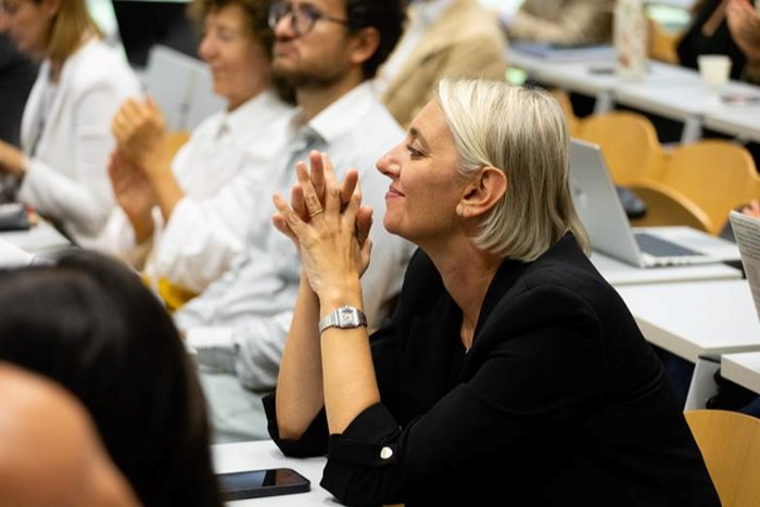 Signora seduta su un banco, compiaciuta, che si sta godendo una lezione.
