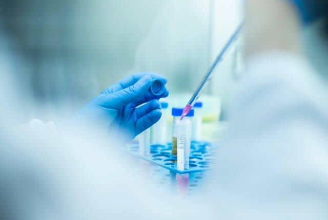 Mani che lavorano con provette in laboratorio
