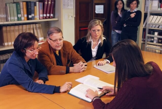 Una studentessa con i docenti durante un esame all'università