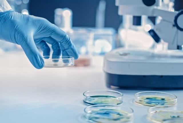 Mano di un ricercatore che lavora al microscopio