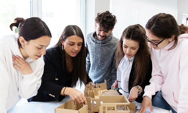 Docente che costruisce un plastico con studenti