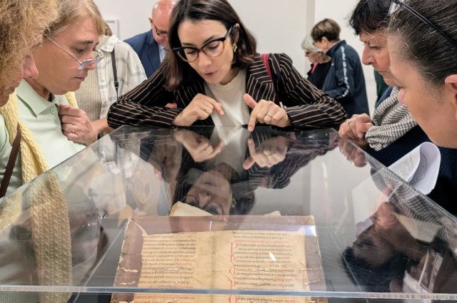 Persone guardano un manoscritto della mostra