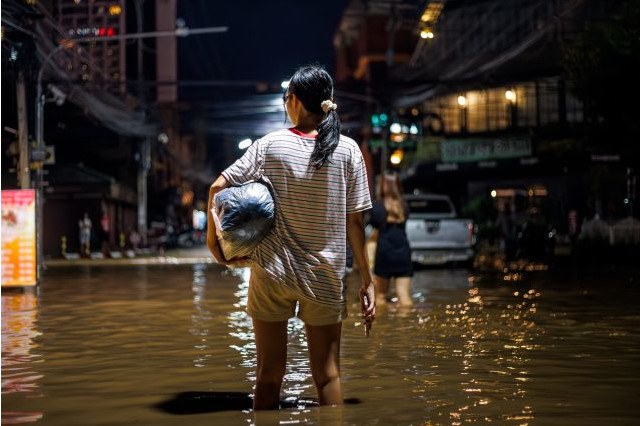 Scena di un film: una donna attraversa un strada alluvionata