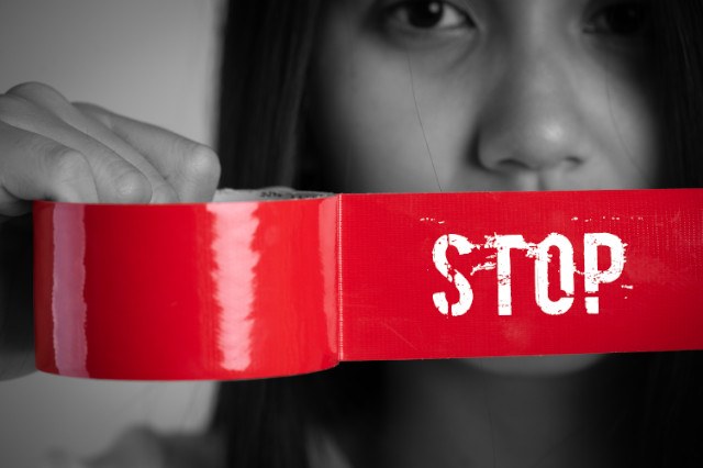 Ragazza che tiene in mano un nastro adesivo con la scritta "Stop"