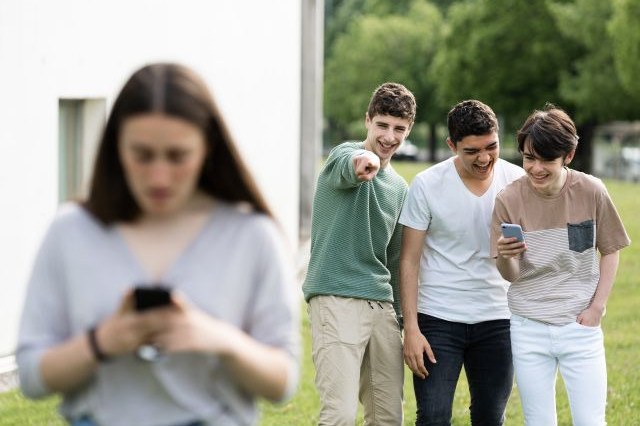 Gruppo di ragazzi de deride una ragazza